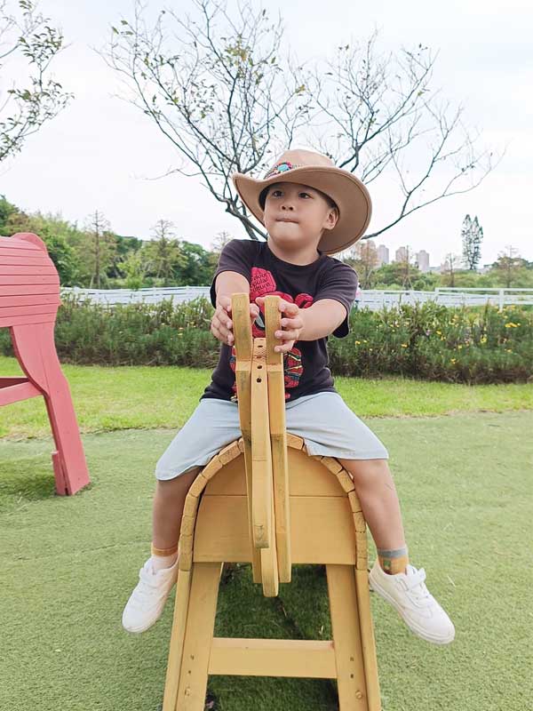 新北三芝牛仔莊園-發現三芝親子景點的樂趣,親子樂趣無窮|豬弟弟|北投之家分享寶寶喜悅|北投之家 新北三芝牛仔莊園|發現三芝親子景點的樂趣,親子樂趣無窮01
新北三芝牛仔莊園的一大特色就是其各式各樣的有趣體驗設施。例如,你可以看到豬弟弟正在騎在一座木製的馬椅上,他臉上洋溢出的帥氣足以讓我們感受到他此時的快樂與滿足。這裡的每一個設施都充滿了牛仔風格,讓人感覺彷彿走進了美國西部的牛仔世界。